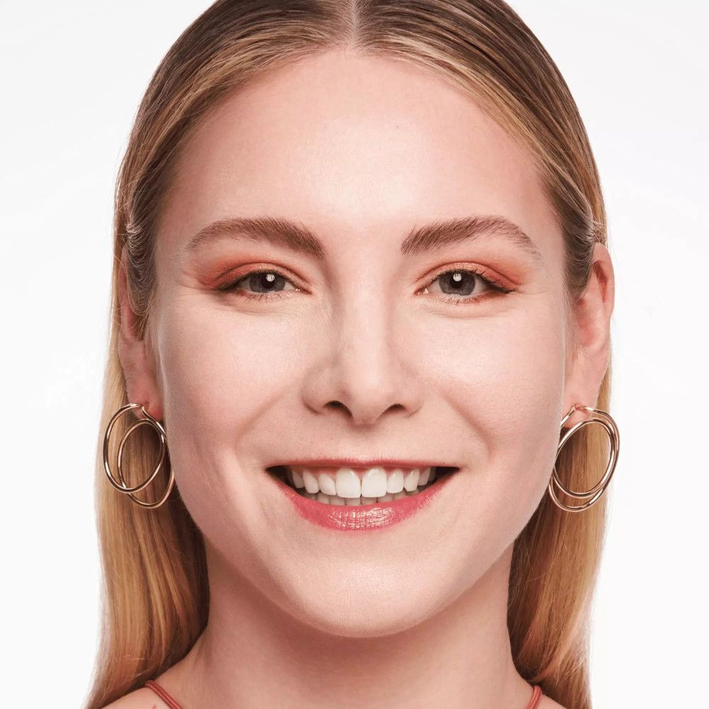 Portret van een vrouw met blond haar. Ze lacht. Ze draagt gouden oorbellen.