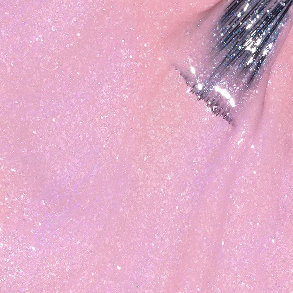 Roze nagellak met glitter. Kwast in de vloeistof. Close-up.