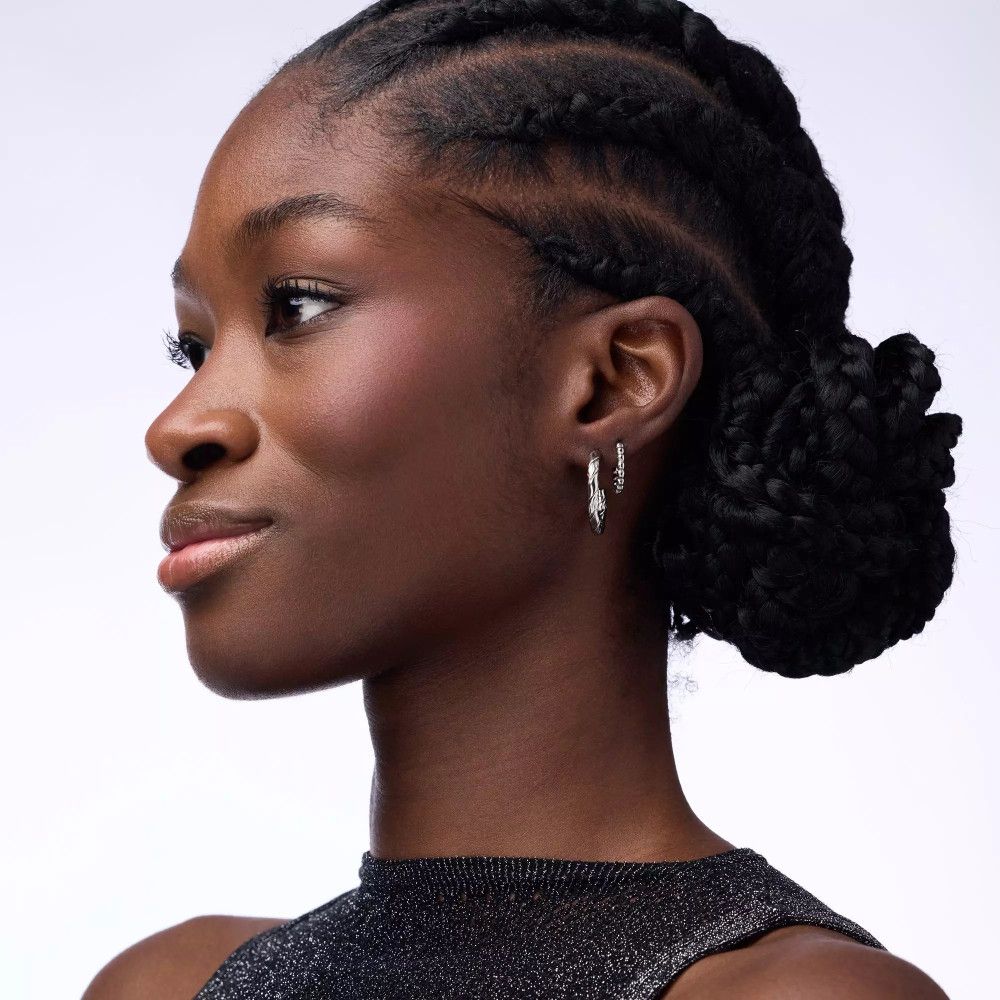 Portrait d'une femme avec des tresses. Fard à joues sur les joues. Elle porte des boucles d'oreilles.