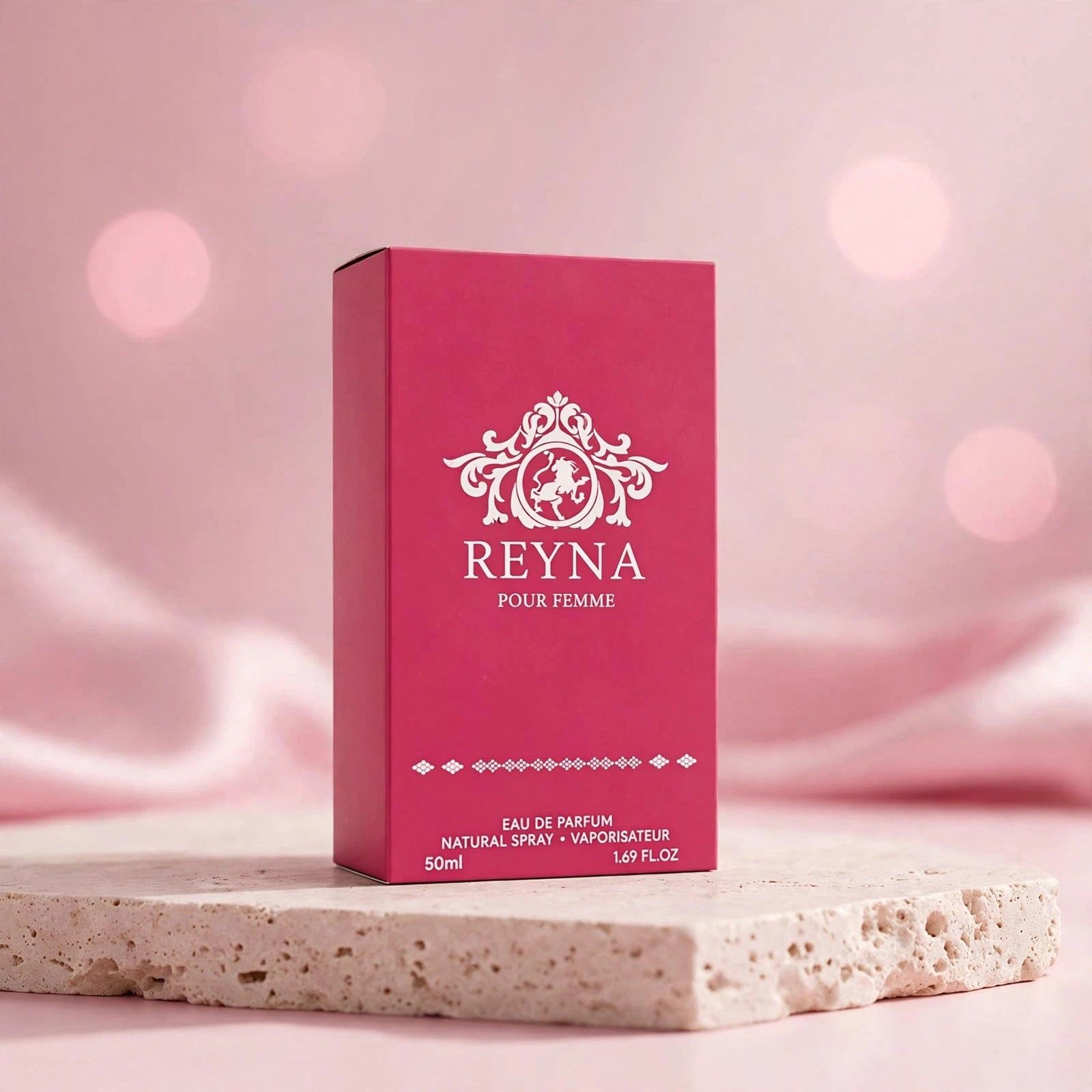 Boîte de parfum rose avec logo argenté et inscription 'REYNA POUR FEMME'.