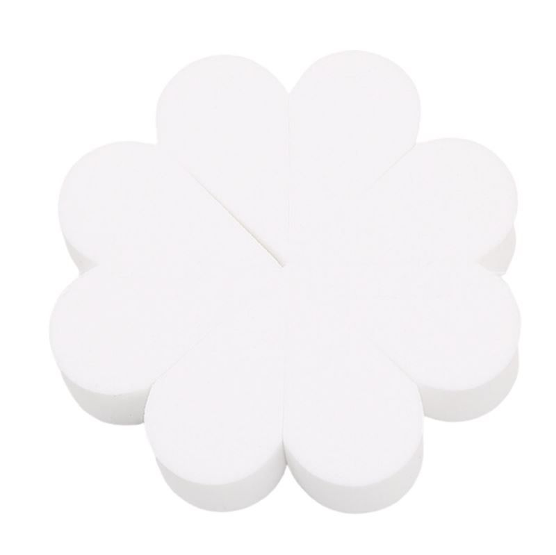 Een enkele set van zes witte, druppelvormige make-upsponzen, gerangschikt in een bloemvormige formatie op een witte achtergrond.