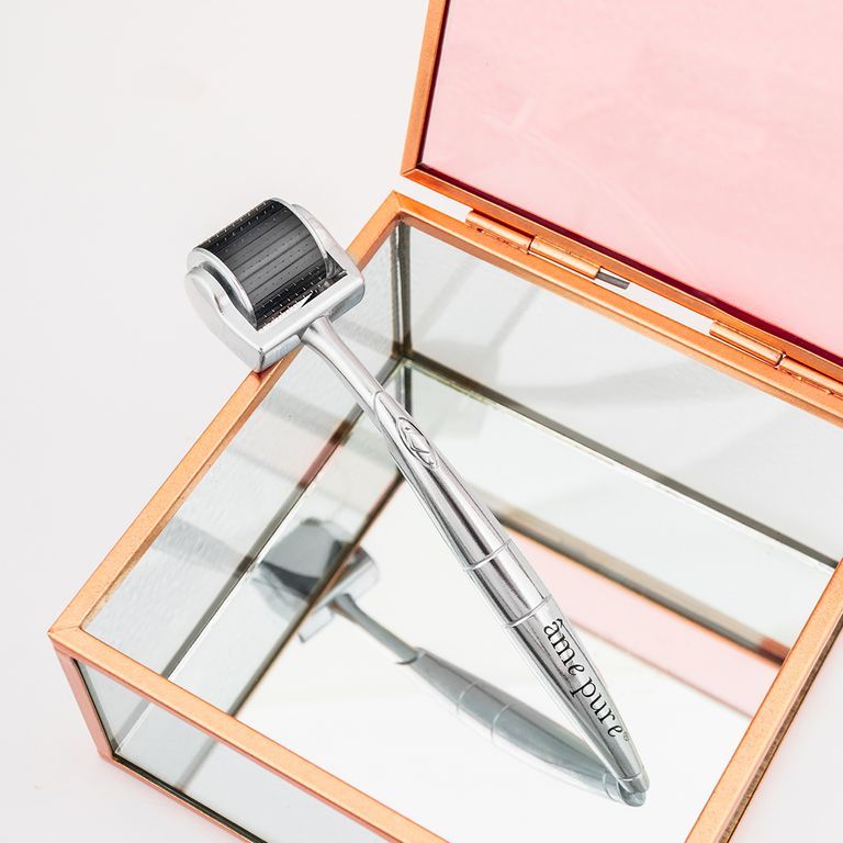 Zilverkleurige CIT Face Roller met zwarte rolkop op een spiegelend sieradendoosje.