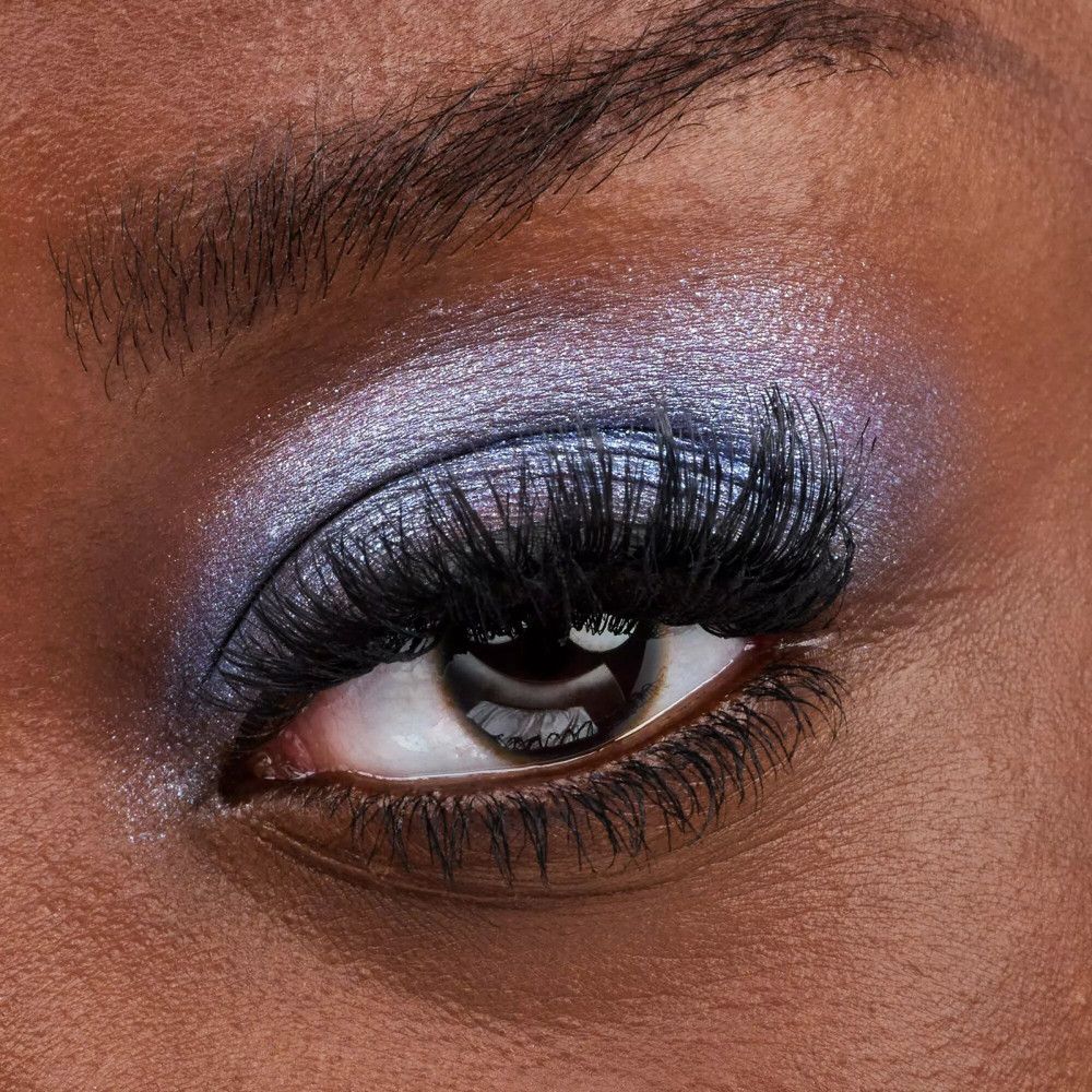 Gros plan sur un œil avec fard à paupières bleu et cils volumineux.