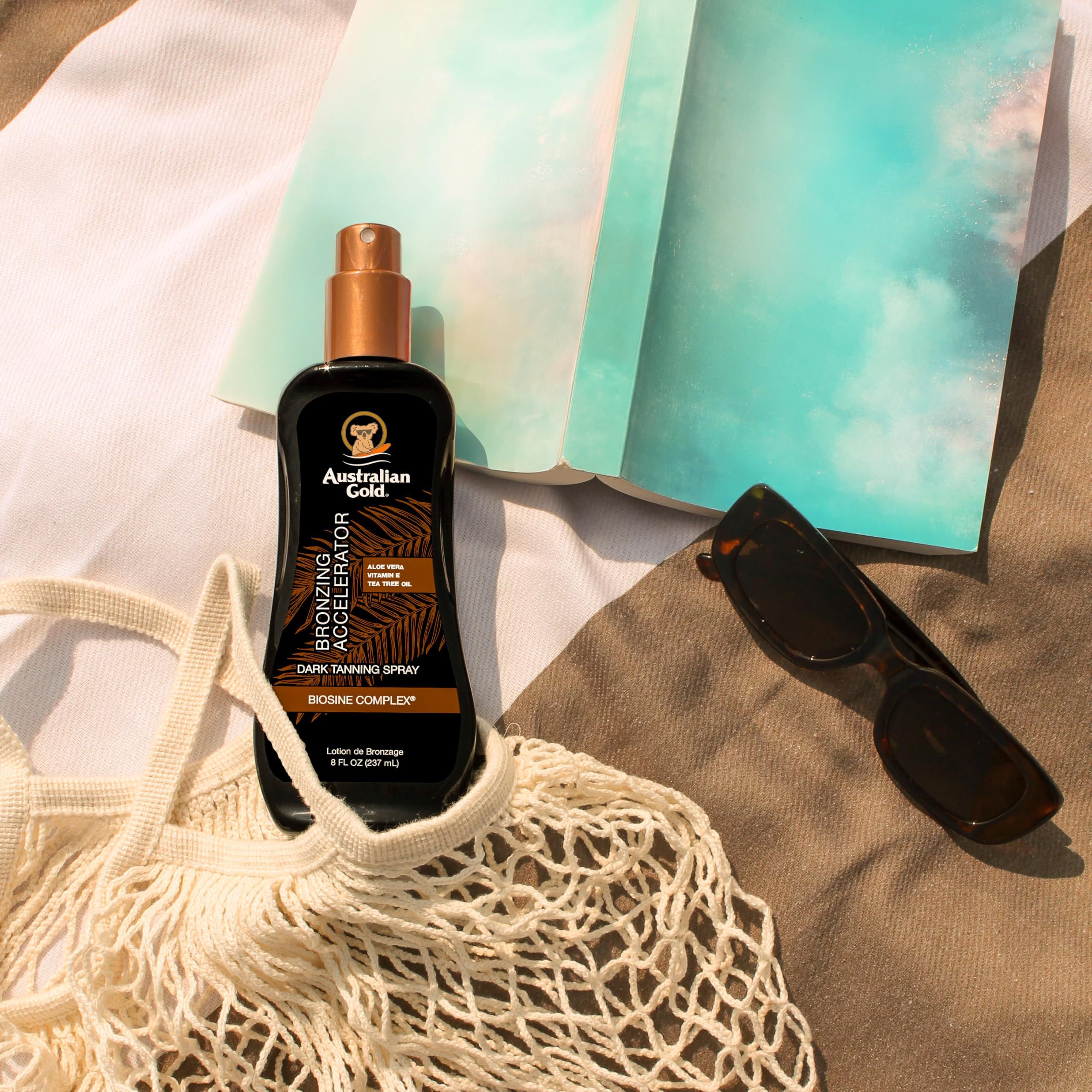 Gel spray bronzant sur une serviette de plage. À côté, lunettes de soleil et carnet. Inscription: Australian Gold, Bronzing Accelerator.