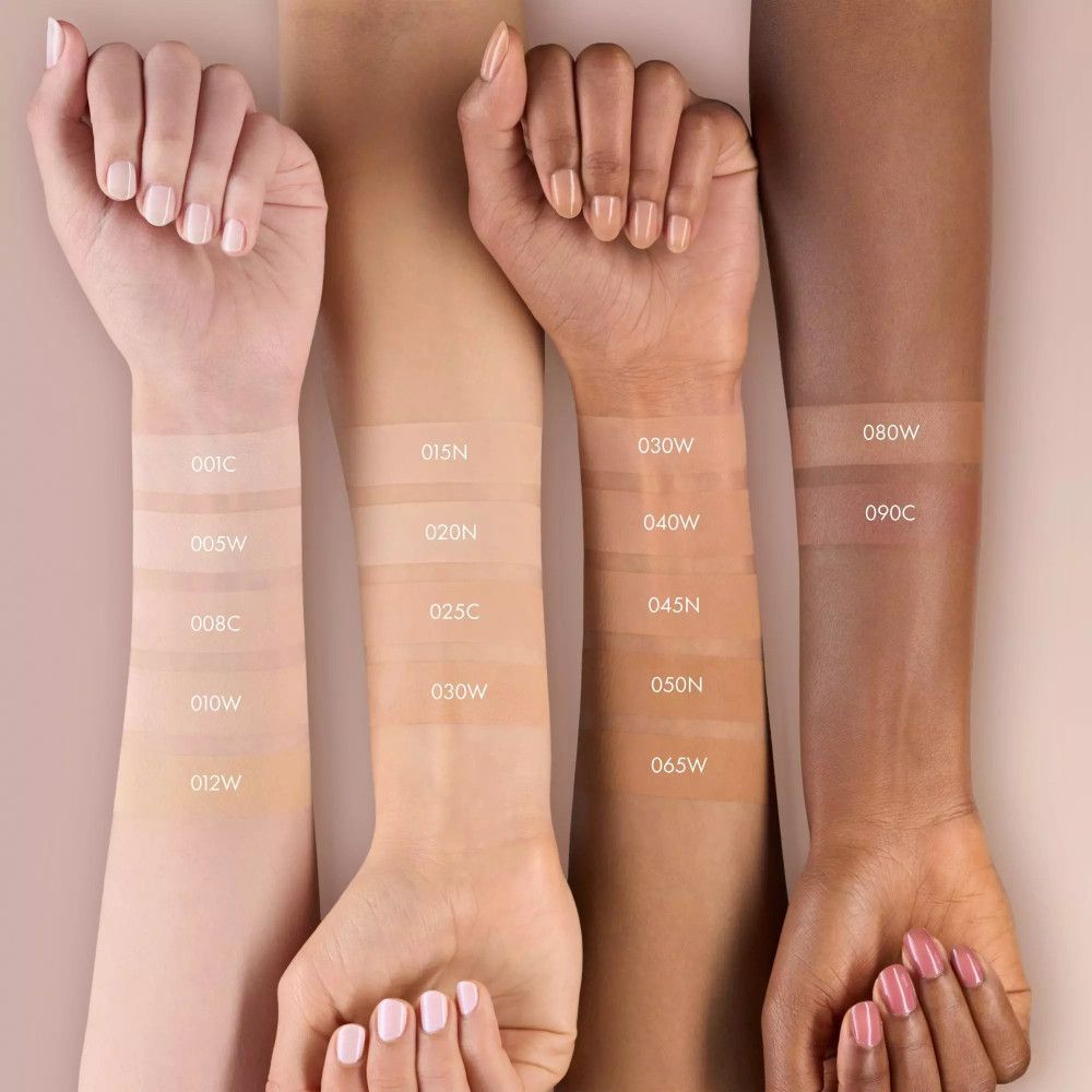 Bras avec différents tons de peau. Échantillon de fond de teint appliqué. Étiquettes avec numéros de couleur.
