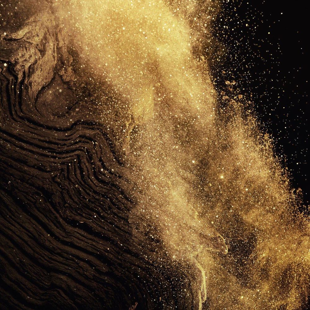 Représentation abstraite de poussière d'or et de surfaces sombres et texturées. Particules claires sur fond sombre.