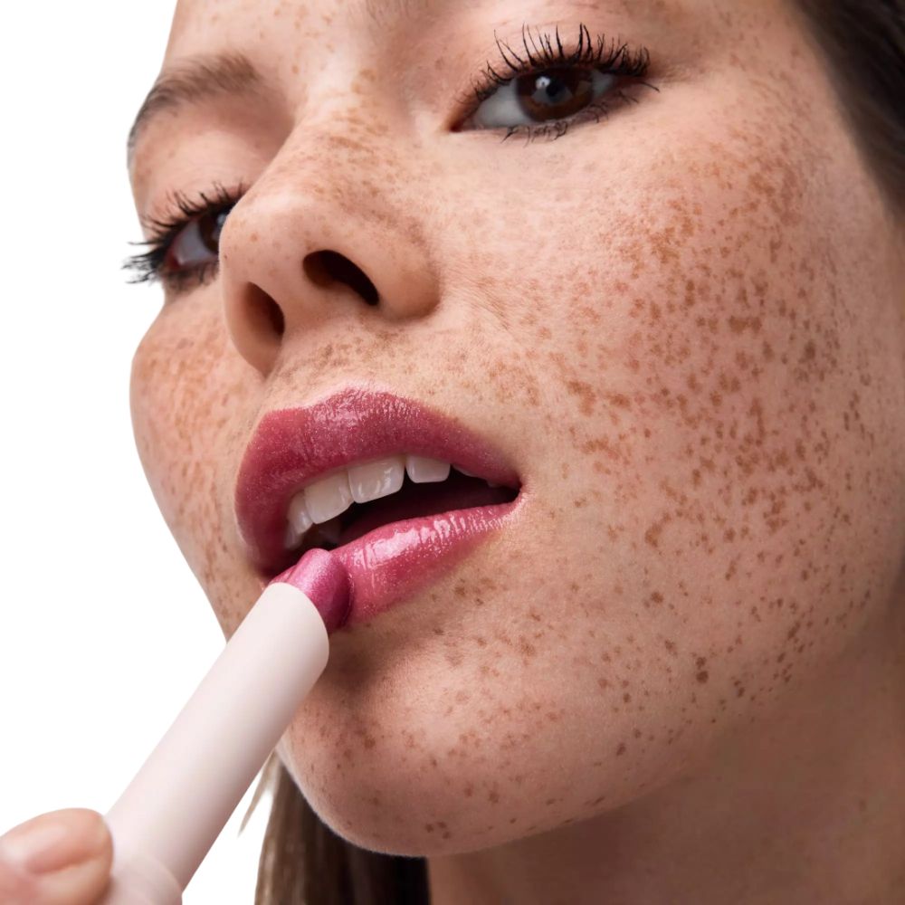 Vrouw brengt lipstick aan. Catrice Diamond Glaze Gloss Stick. Roze lipstick. Close-up.