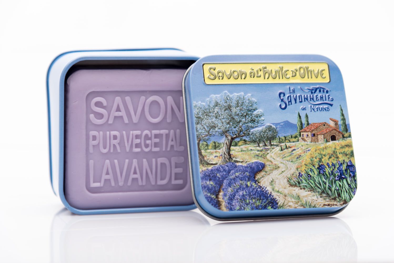 Open blauwe metalen doos met zeep. Zeep met opdruk "SAVON PUR VEGETAL LAVANDE". Doos met landschap en tekst.