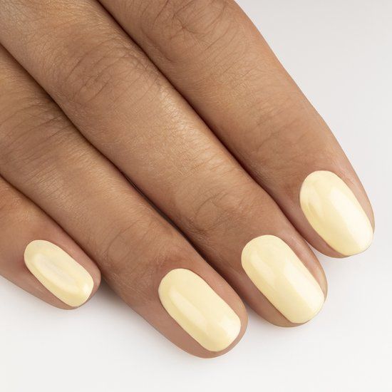 Main avec ongles ovales peints en jaune. Teint de peau brun moyen. Fond blanc.