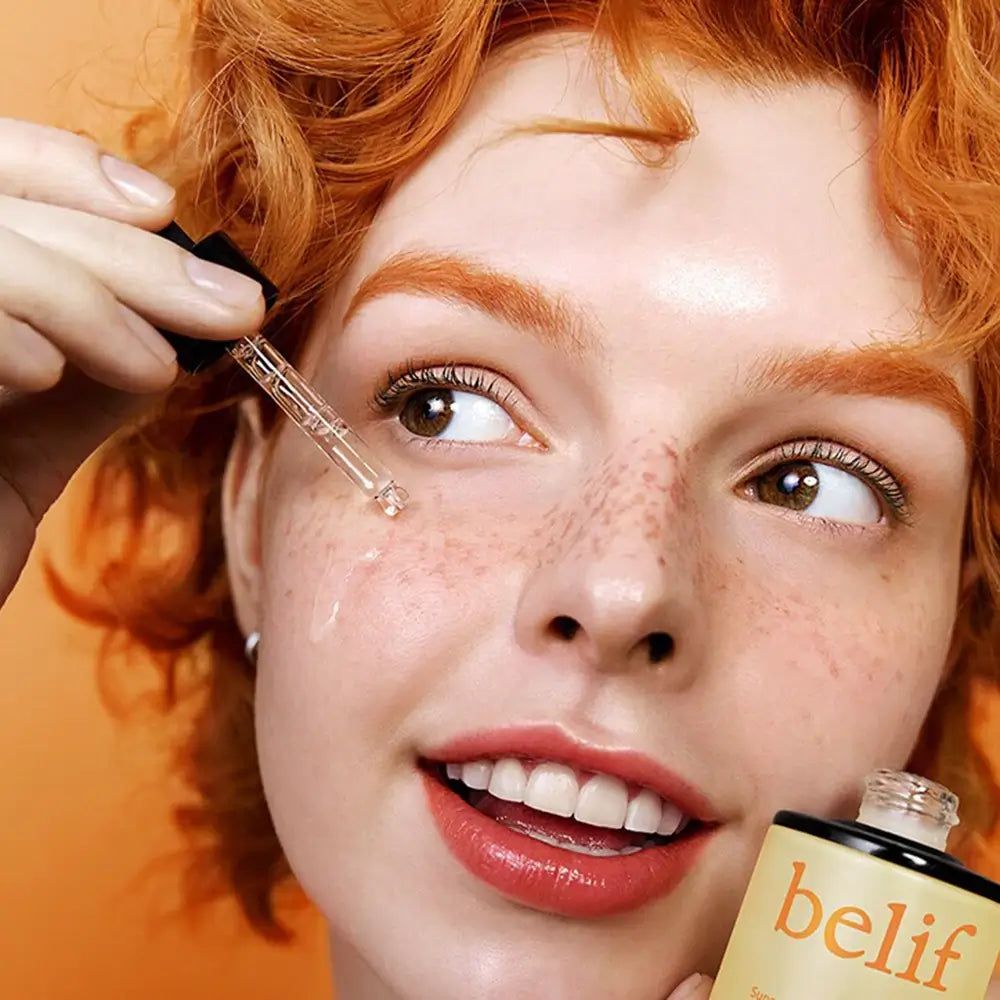Vrouw met sproeten brengt serum aan met druppelaar.