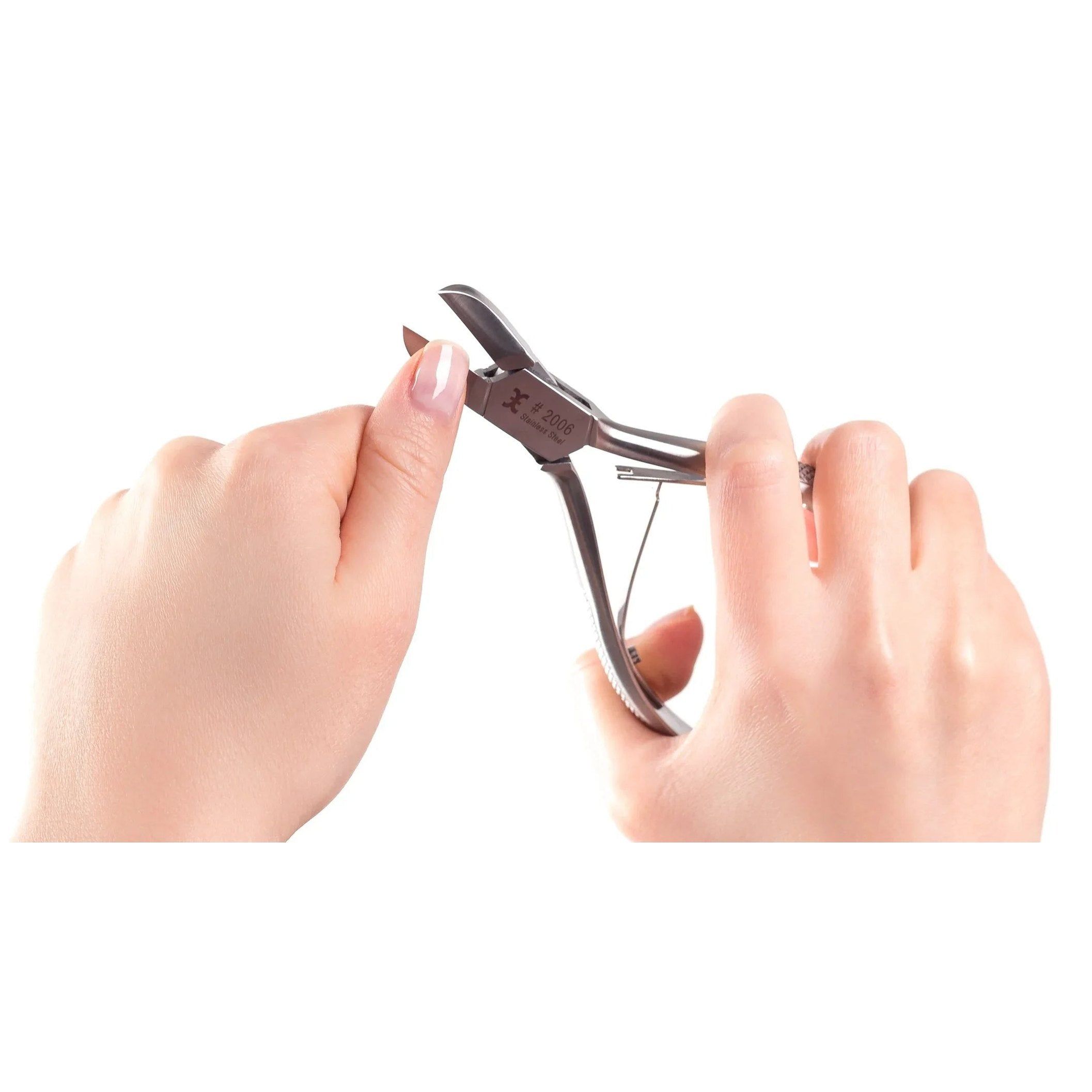 Nagelknipper in gebruik. Handen houden de knipper vast en bewerken een nagel. Witte achtergrond.