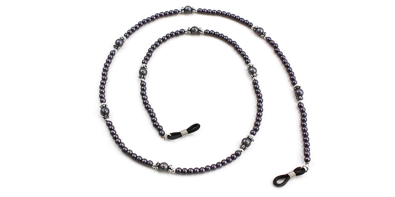 Brillenketting met donkere kralen en zilverkleurige accenten. Twee uiteinden met lussen voor bevestiging aan brilpoten.