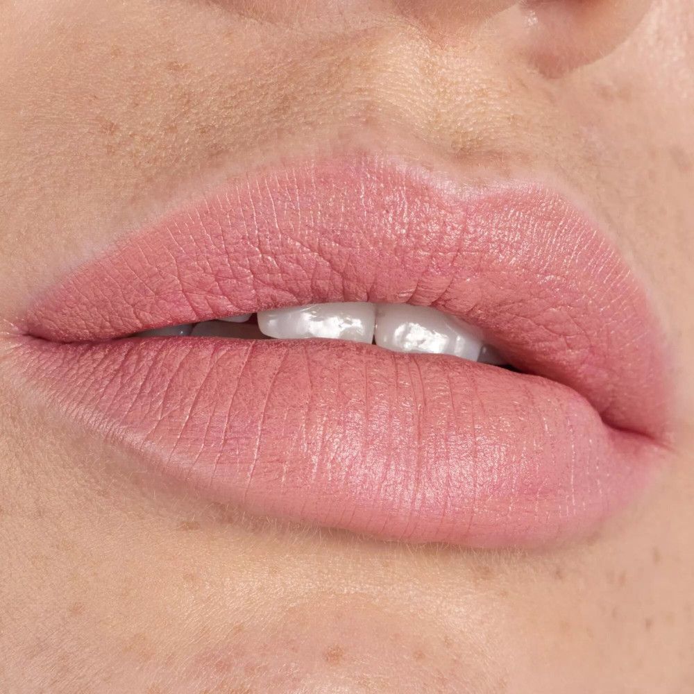 Gros plan sur des lèvres maquillées avec un rouge à lèvres rose clair. Les lèvres sont légèrement entrouvertes.