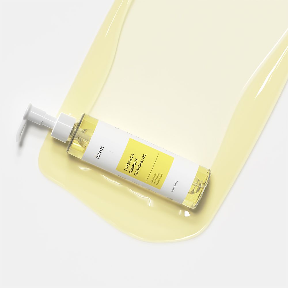 Flacon avec pompe sur liquide jaune. L'étiquette indique "IUNIK Calendula Complete Cleansing Oil".