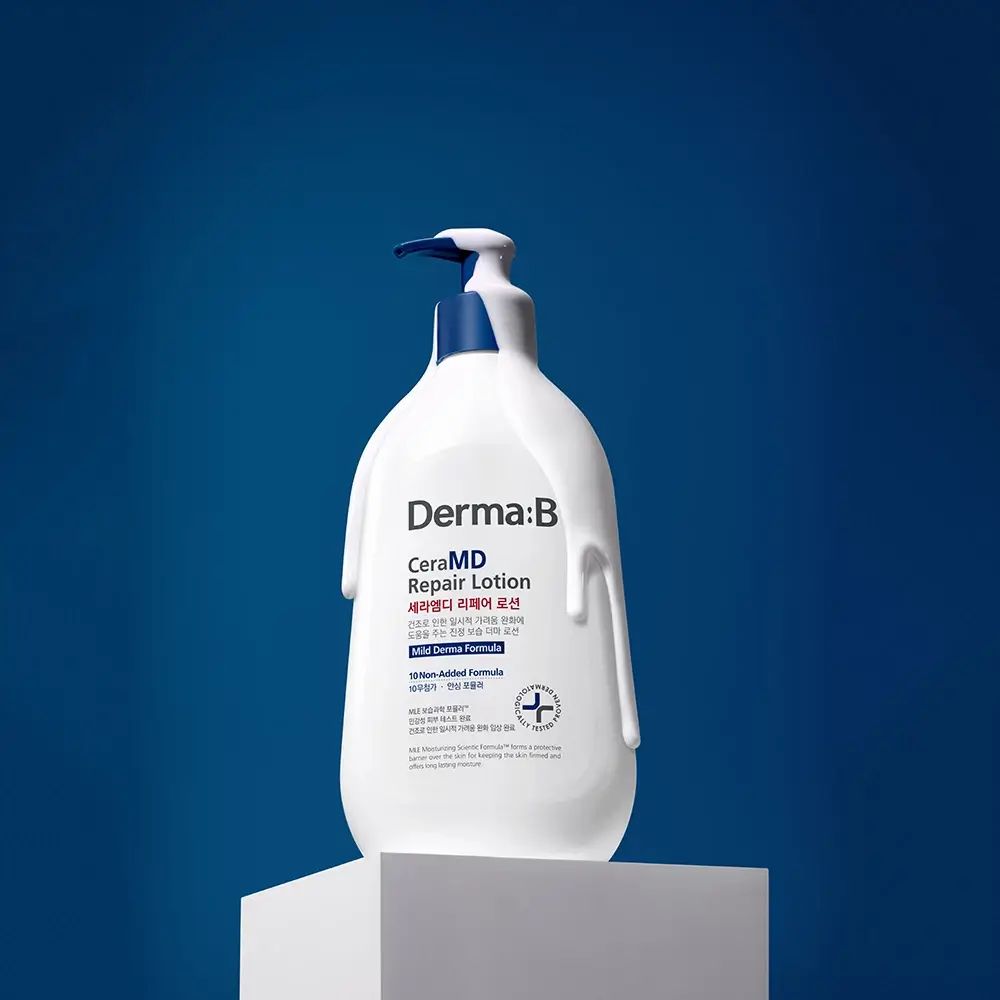 Witte fles met blauwe pomp op een sokkel. Opschrift: Derma:B CeraMD Repair Lotion. Lotion druipt naar beneden.