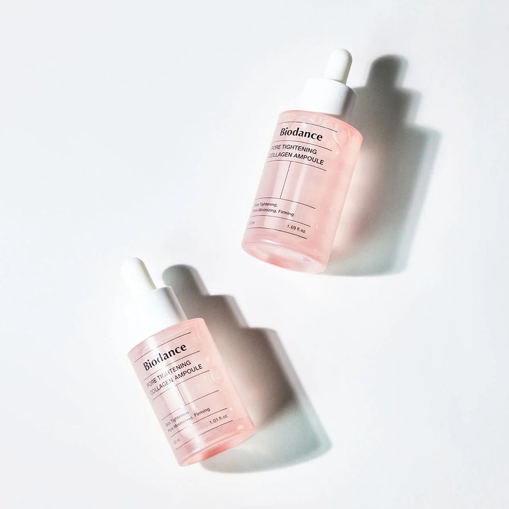 Twee roze flessen met witte dop. Opschrift: Biodance Pore Tightening Collagen Ampoule. Schaduwen.