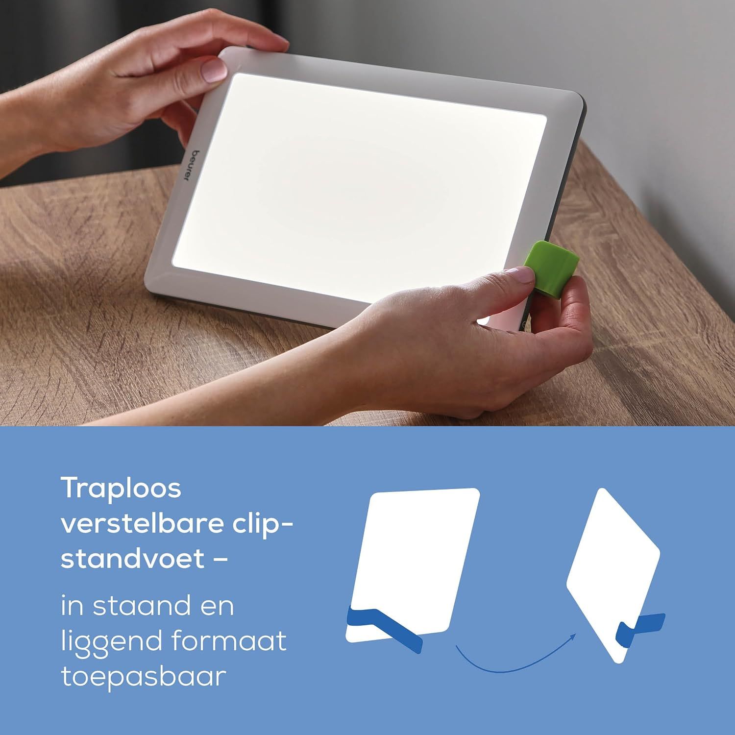 Lichtgevend, rechthoekig apparaat met witte rand, vastgehouden door handen. Een groene clip is bevestigd.