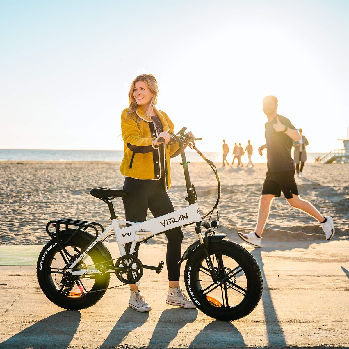 Vélo électrique pliant blanc, pneus noirs. Femme à côté. Vitilan V3 sur le cadre.