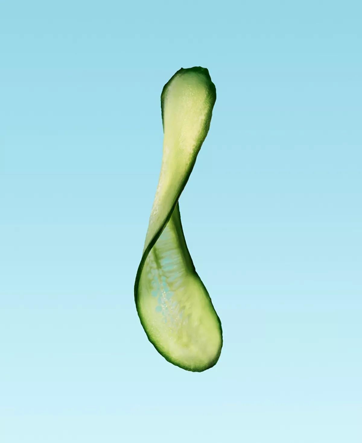 Tranche de concombre courbée. Couleur verte. Sur fond bleu.