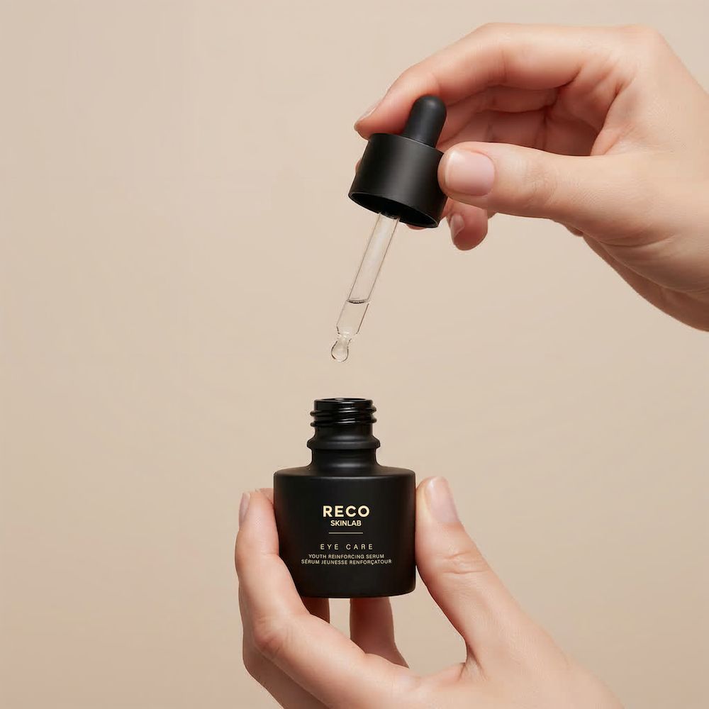 Mains tenant un flacon noir RECO SKINLAB Eye Care. Le compte-gouttes est inséré dans le flacon.