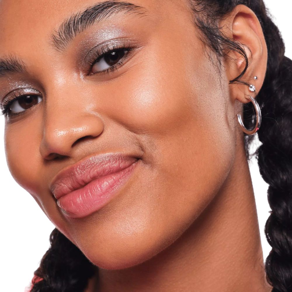 Gros plan d'une femme avec fard à paupières pailleté argenté sur les paupières. Elle sourit.