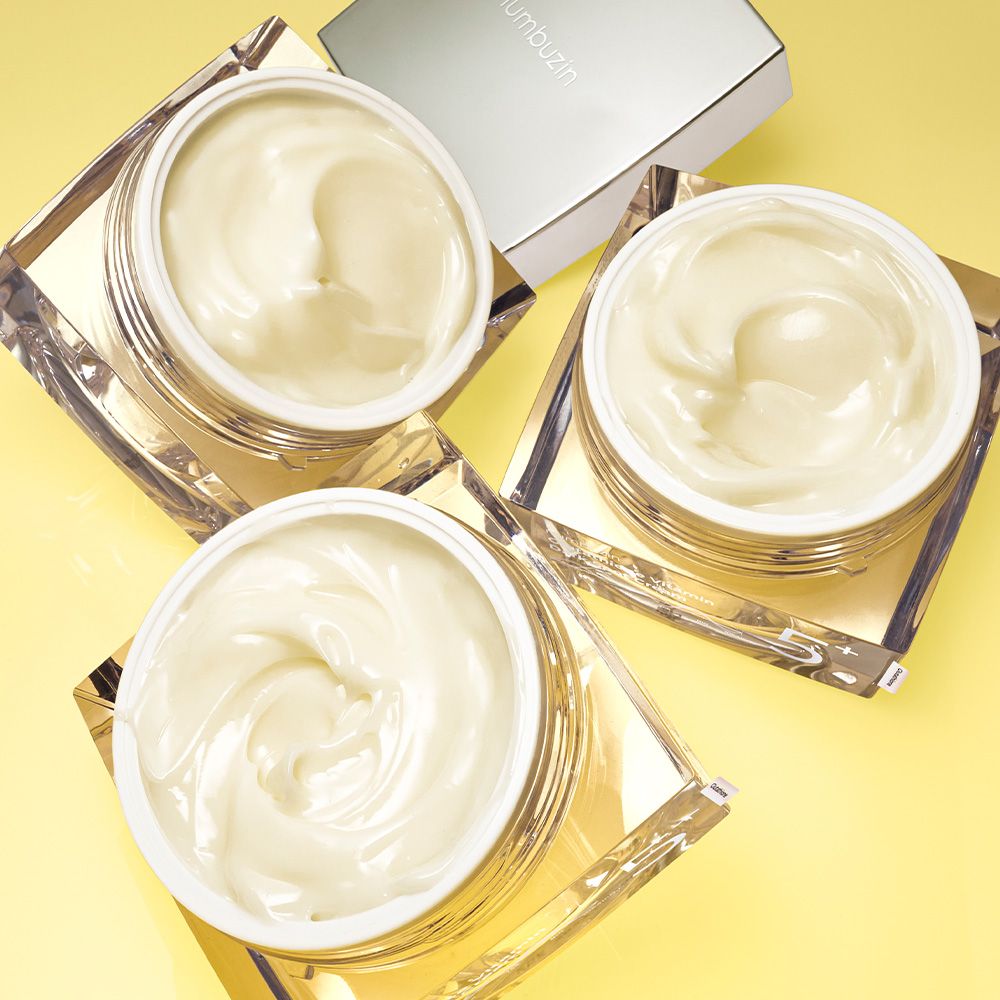 Drie open potten met NUMBUZIN Nr.5 Vitamine Glutathion Dark Spot Laser Creme op gele achtergrond.