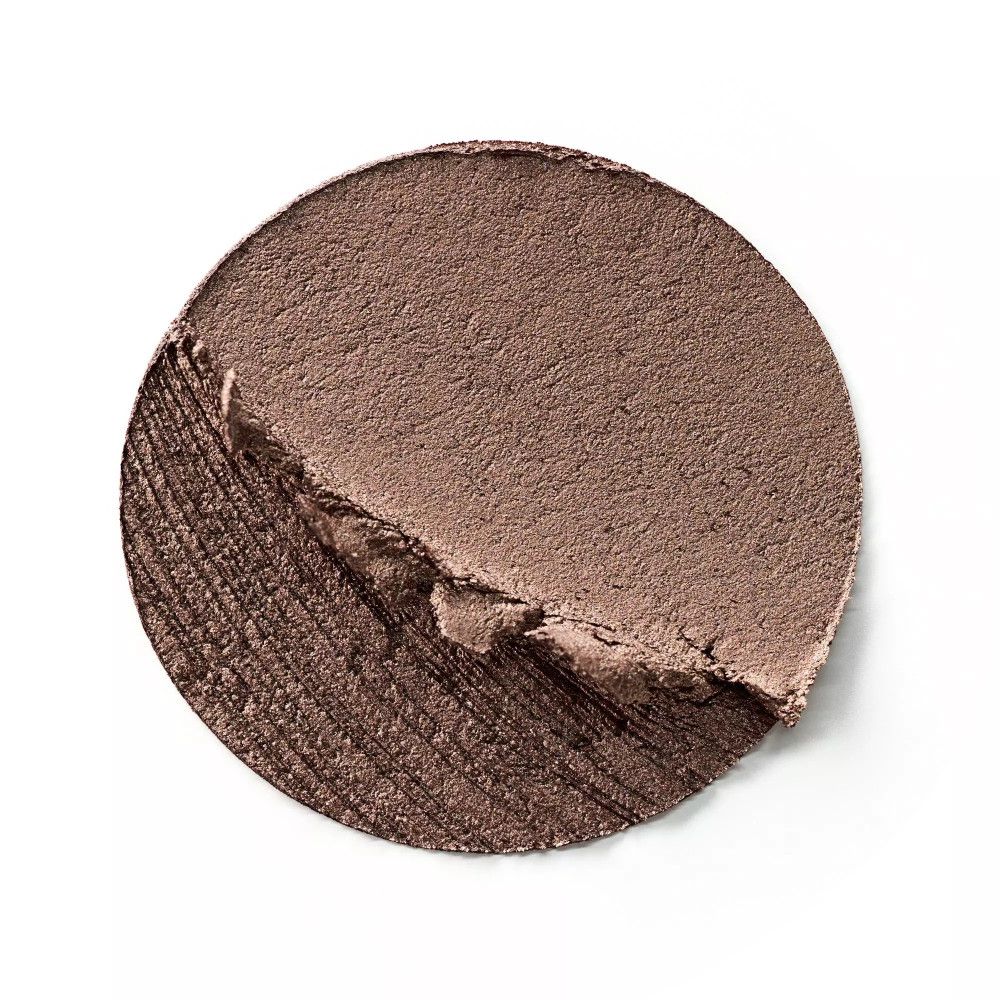 Échantillon rond d'ombre à paupières crème. La texture est crémeuse et marron. Une partie est enlevée.