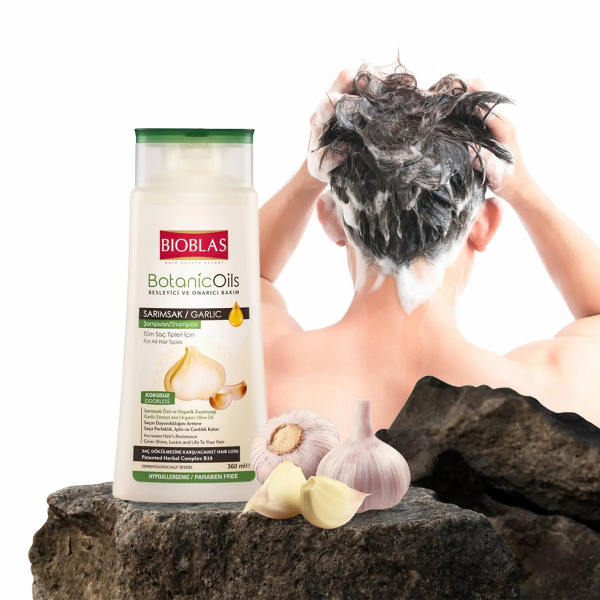 Bioblas BotanicOils shampoo met knoflook. Fles en knoflook op steen. Persoon wast haar.