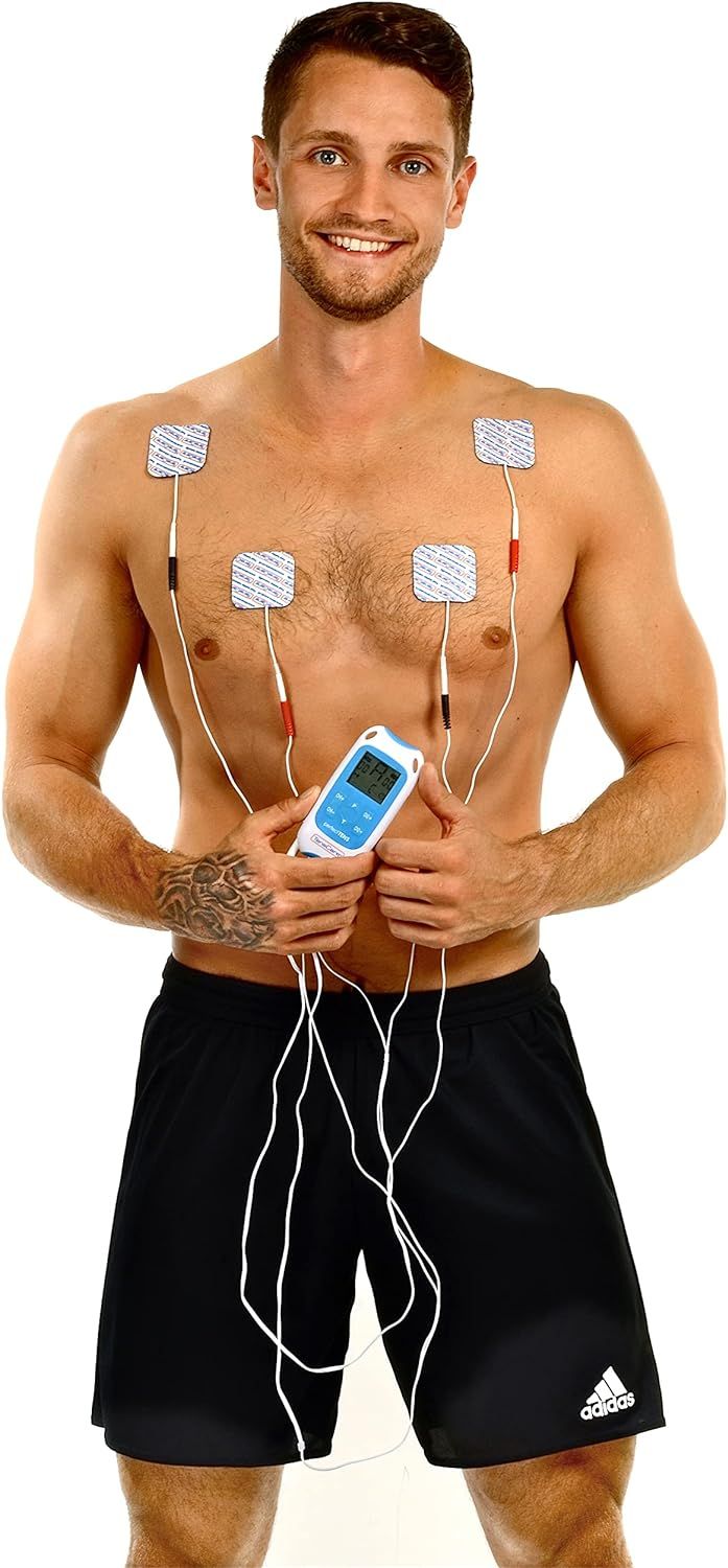 Man met elektrodepads op borst, houdt TENS-apparaat vast. Zwarte shorts. Geen verdere details zichtbaar.