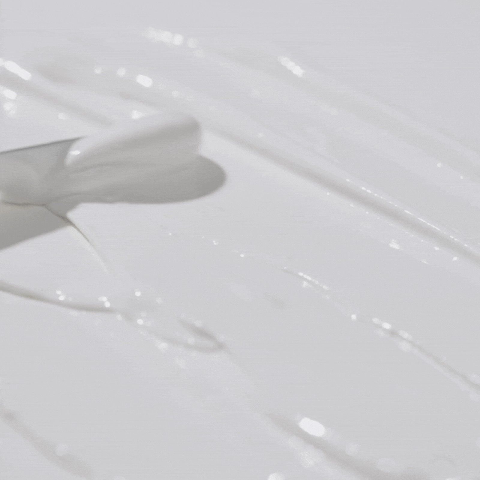 Crème solaire blanche en traînées sur fond blanc.