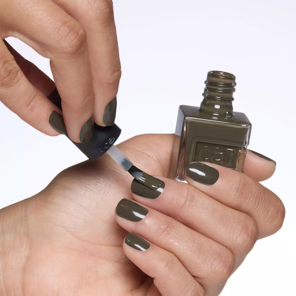 Main vernissant les ongles avec un pinceau. Flacon de vernis à ongles avec logo de la marque.