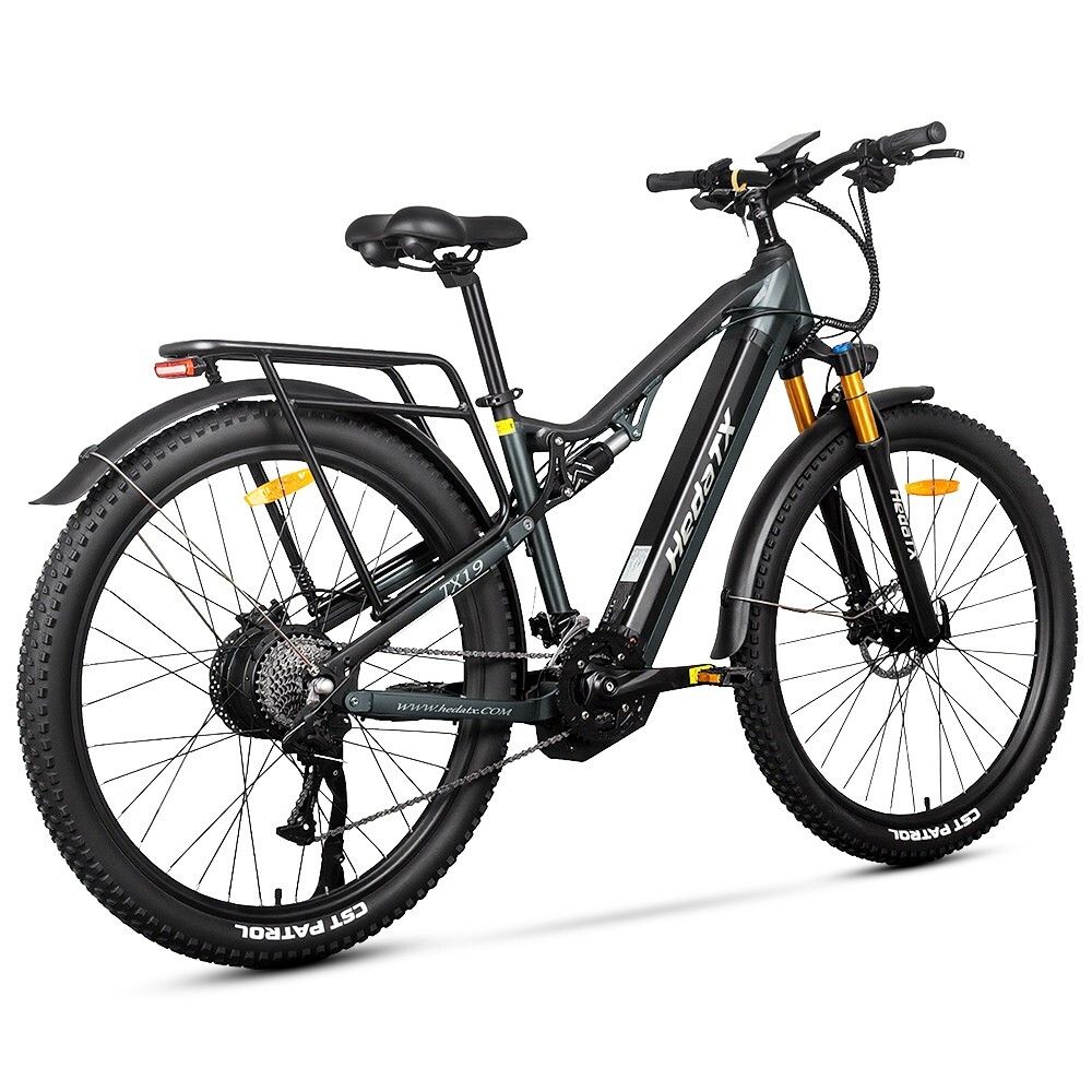 Vélo électrique gris HedaTX TX19. Pneus noirs, porte-bagages, suspension. Fourche jaune. 27 vitesses. Inscription HedaTX.