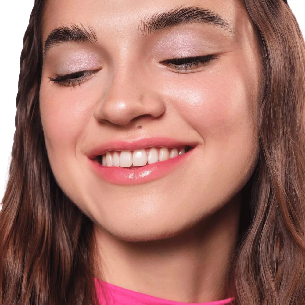 Gros plan d'un visage souriant avec fard à paupières. Les paupières sont recouvertes d'une légère brillance.