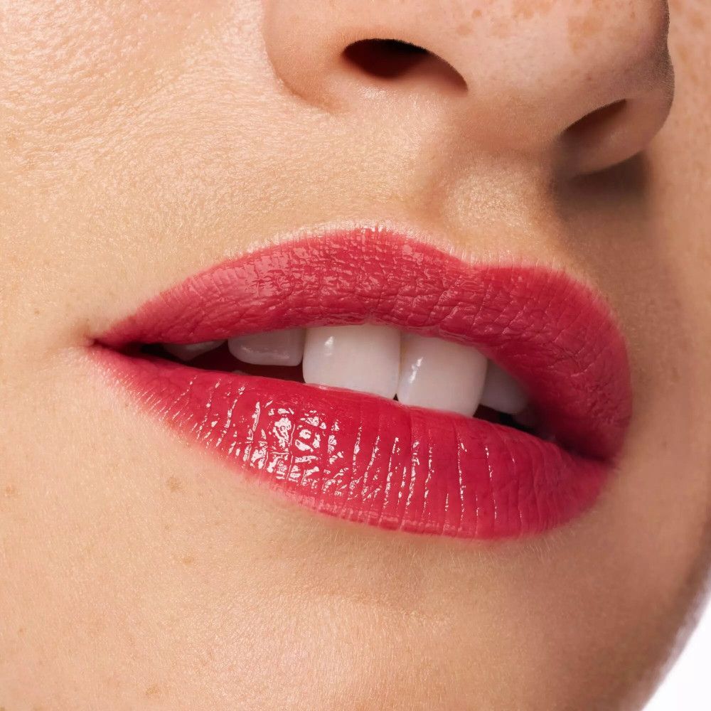 Gros plan sur des lèvres avec du rouge à lèvres rouge. Fini brillant. Dents blanches visibles.
