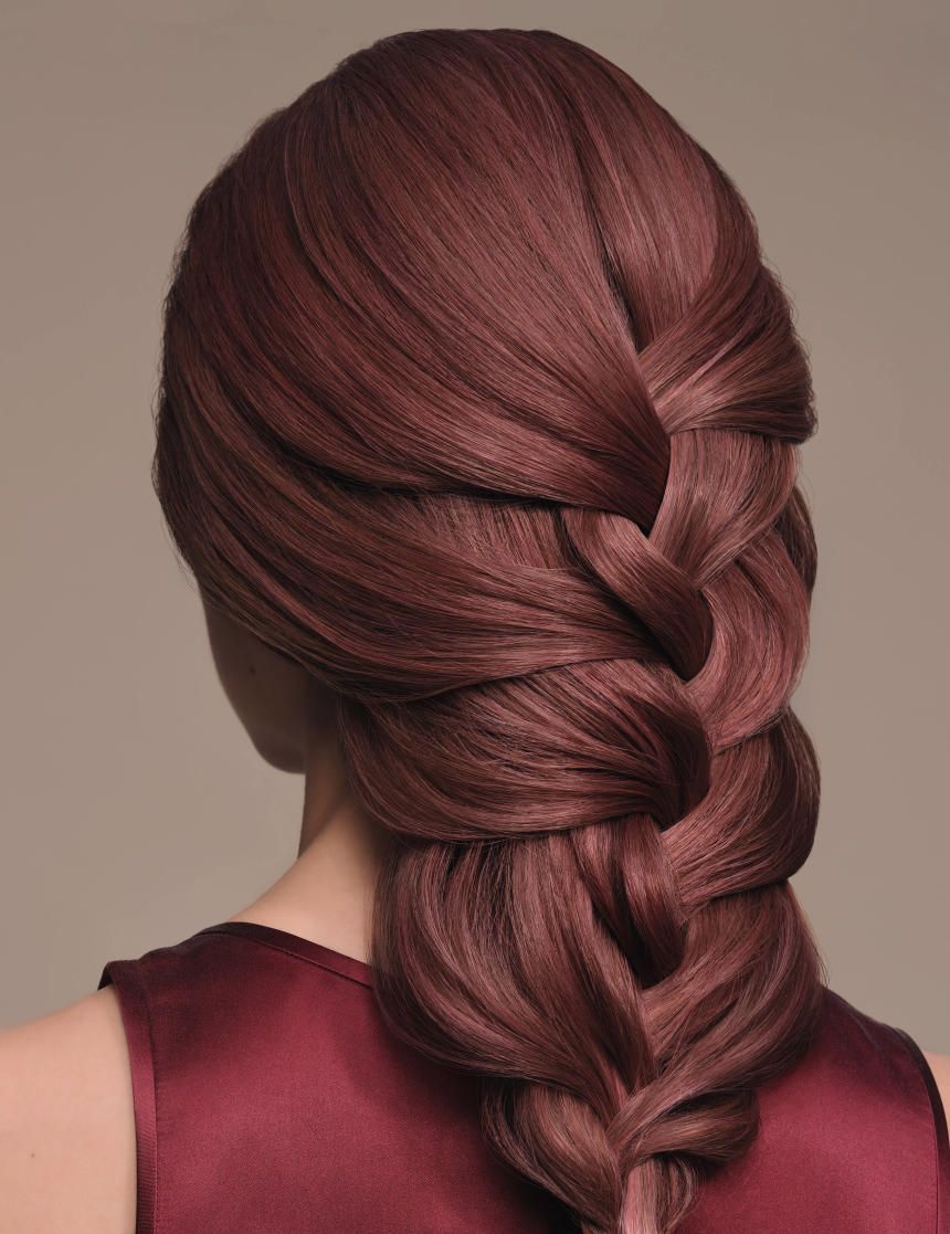 Achteraanzicht van een persoon met gevlochten, rood geverfd haar. Persoon draagt een bordeauxrode top.