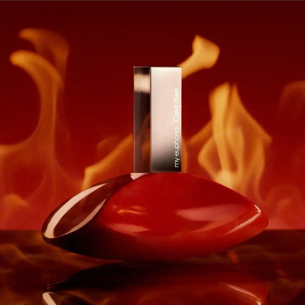 Flacon rouge avec bouchon argenté. Inscription: my euphoria Calvin Klein. Fond: flammes.