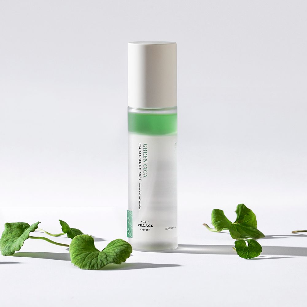 Cilindrische fles met groene band en witte dop. Opschrift: Green Cica Facial Serum Mist. Merk: Village 11 Factory. Met bladeren.
