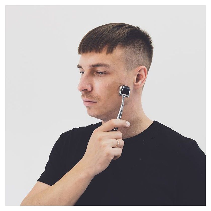 Un homme utilise un rouleau Derma ame pure sur son visage.