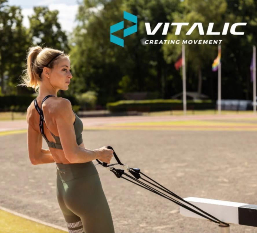 Femme s'entraînant en extérieur avec des bandes de résistance. Bandes noires avec poignées. Logo VITALIC en arrière-plan.