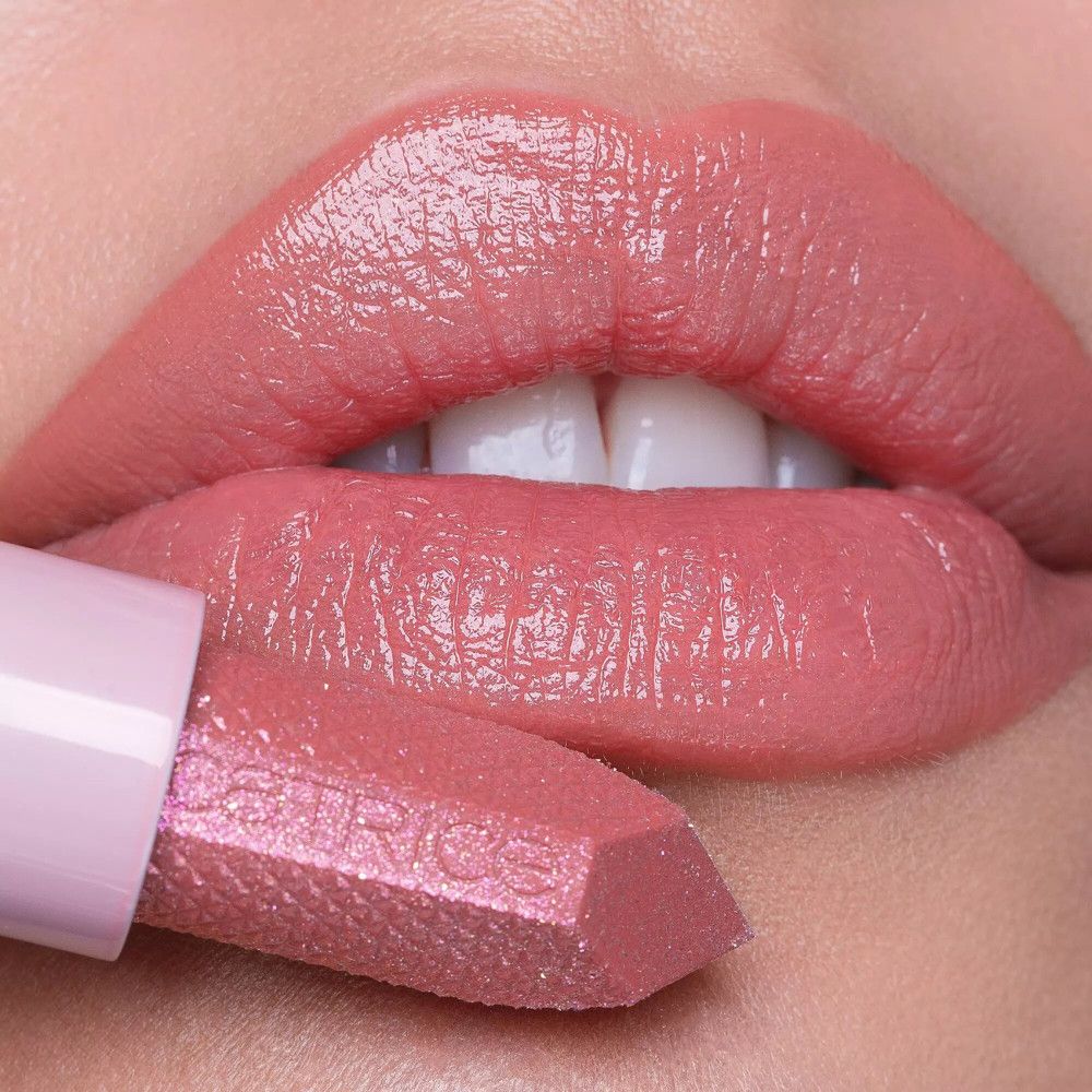 Mond met aangebrachte lippenbalsem. Lippenstift in de hand. Roze tint.