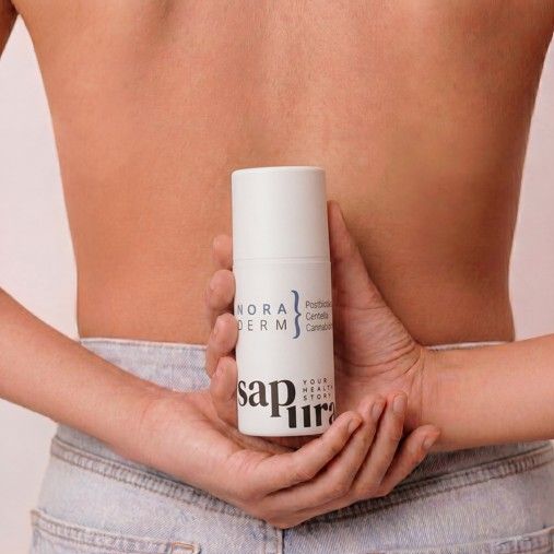 Persoon houdt witte fles met pompdosering, opschrift 'NORADERM' en 'sapura', achter de rug.