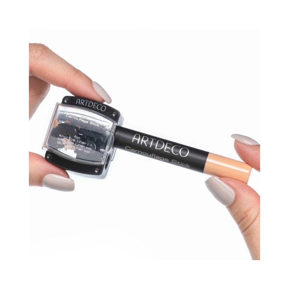 Duo taille-crayon Artdeco. Taille-crayon noir avec couvercle transparent. Un stick camouflage est tenu.