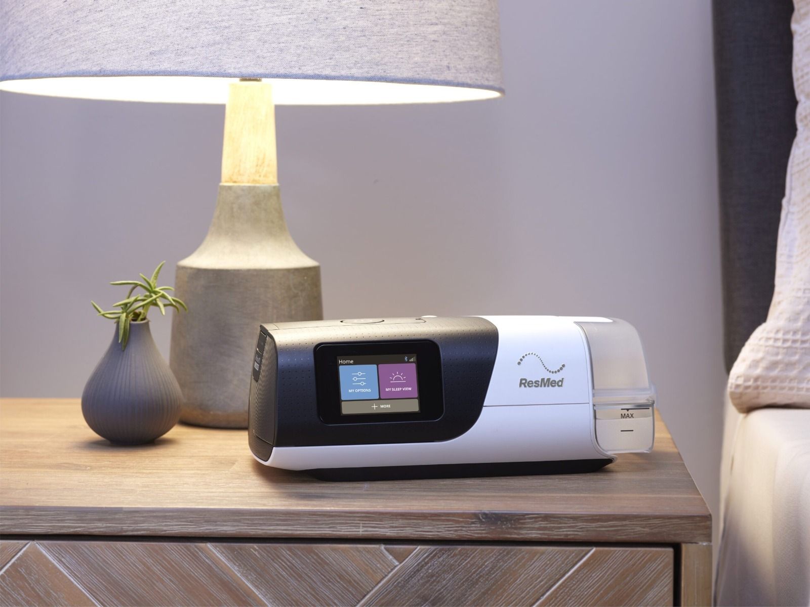 ResMed AirSense 11 op nachtkastje naast lamp en vaas.