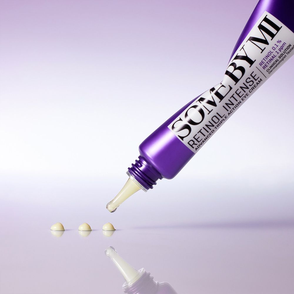 Tube de crème contour des yeux SOMEBYMI Retinol Intense avec une goutte et trois perles de produit.