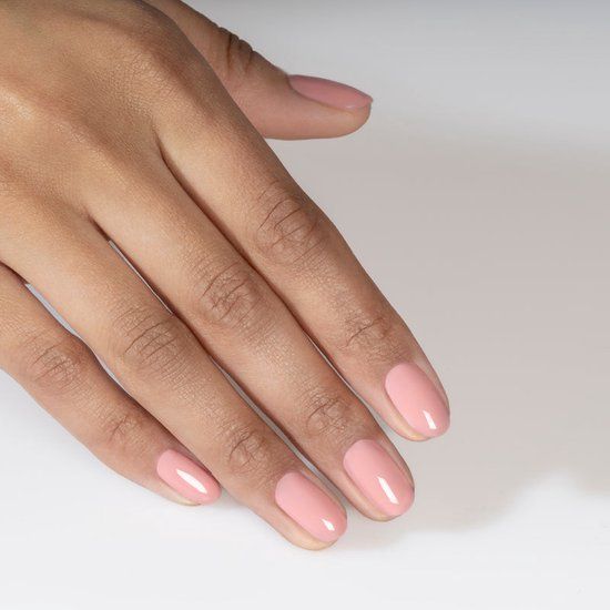 Main avec ongles vernis en rose. Ongles brillants, de forme ovale.