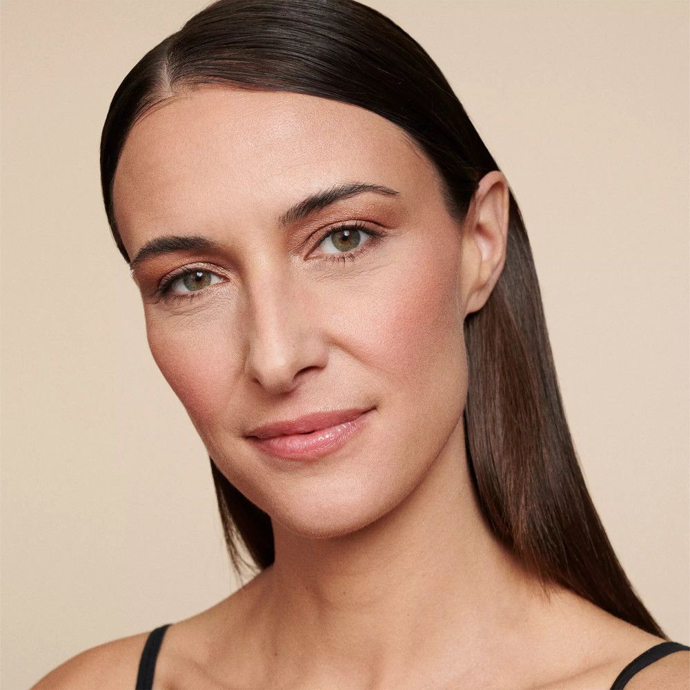 Portrait d'une femme maquillée. Peau bronzée, joues roses, cheveux bruns.