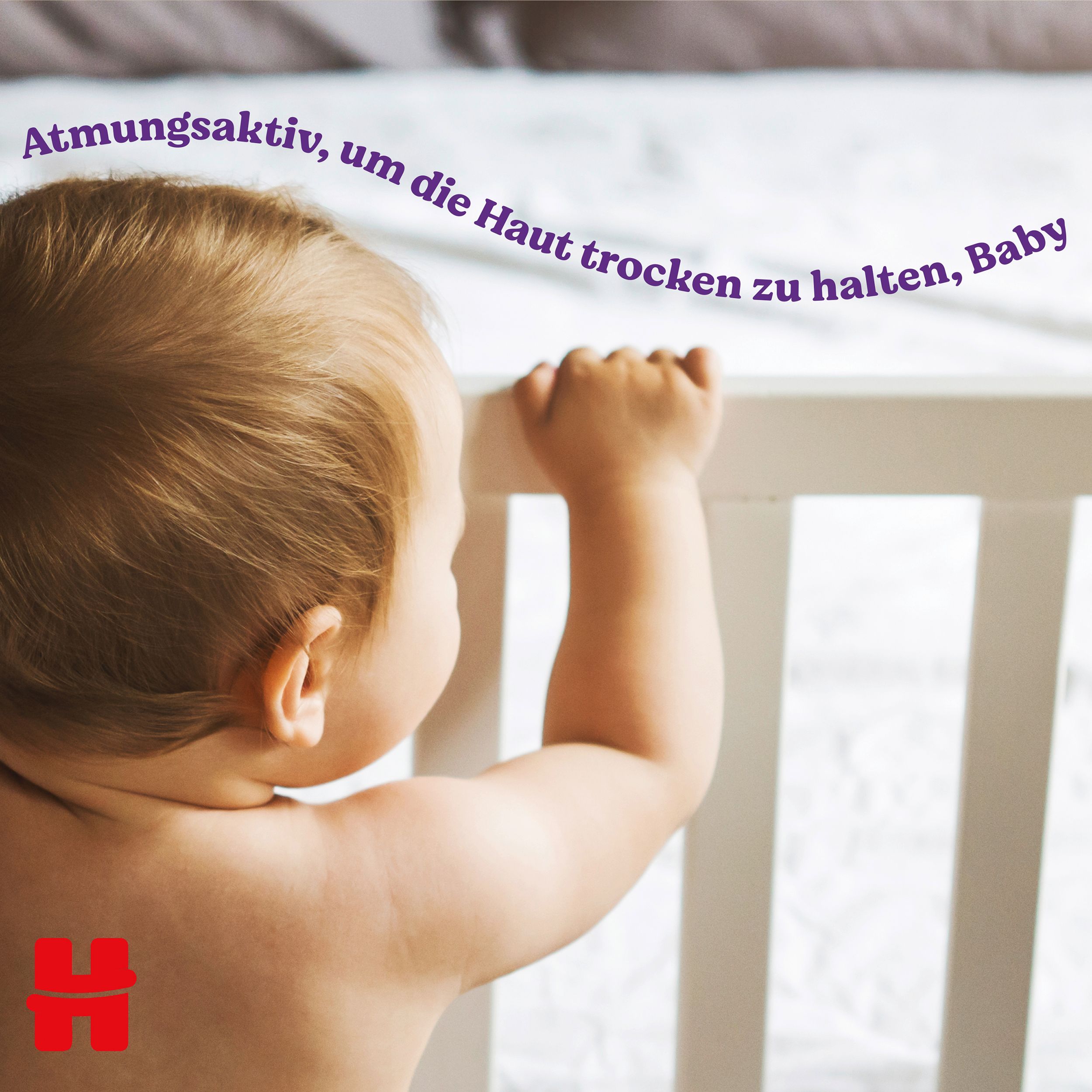 Baby kijkt over de rand van een babybedje. Tekst: Ademend om de huid droog te houden, baby.