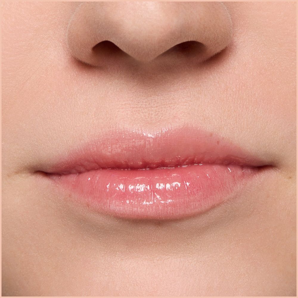 Gros plan sur des lèvres avec un gloss brillant. Teinte rose.