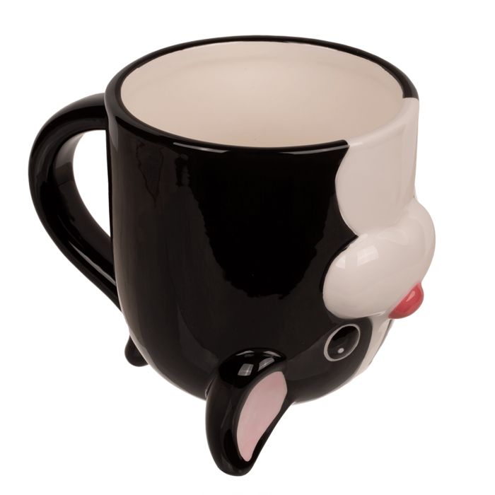 Zwarte beker, wit gezicht, roze tong, oor. Keramiek. Bovenaanzicht.