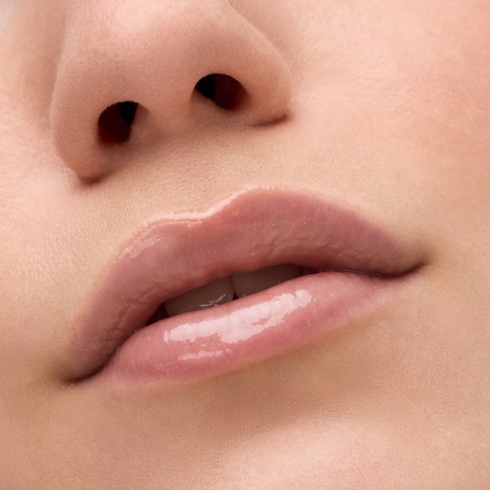 Close-up van lippen met lipelixer. Glanzende, roze glans op de lippen.